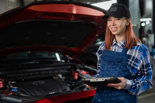 Caucasian female auto mechanic uses a special computer to diagnose faults