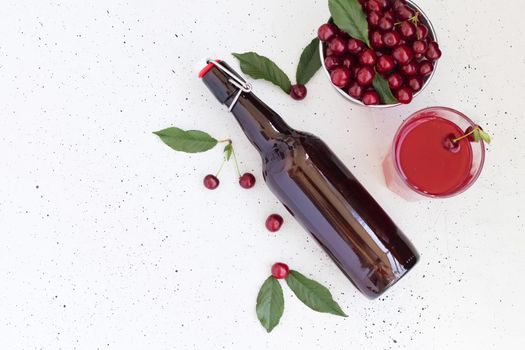 Cold cherry juice in a glass and bottle with ripe berries. Top view, copy space for text. The concept of summer refreshing drink morse or kompot.