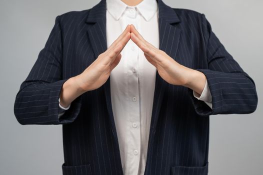 Business woman in a suit holding her hands in the shape of a house