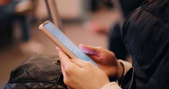 Woman hands using cellphone on active subway train. Female looking for a job online using gadgets on public transportation. Technology concept. Surface on internet.