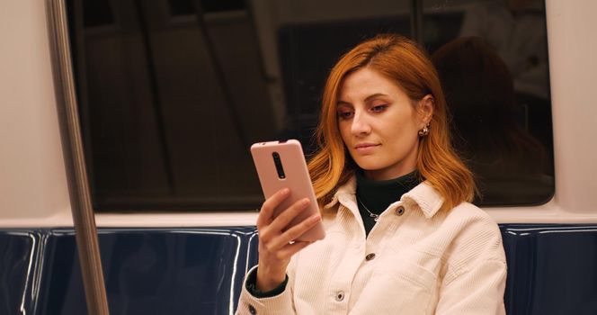 Woman on train using smartphone scrolling. Female chatting with friends. Technology and cellphone in the city. Technology content.
