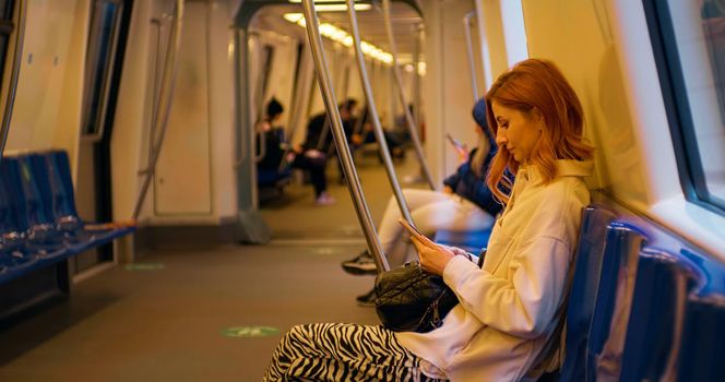 Woman reading on smartphone screen, standing in public transport. Female surfing for information. Internet addiction.