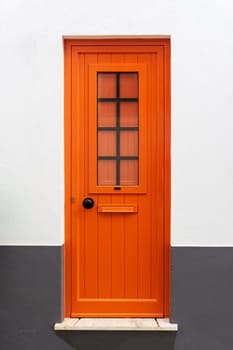 New closed modern bright orange door in a white - gray wall