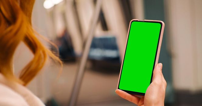 Close up woman watching on green screen phone in public transportation. Using technology on a train. Smartphone addiction. Green Screen Mock Up Chroma Key phone Display.