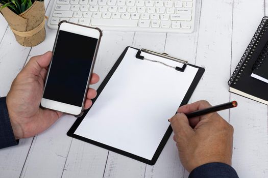 Businessman writing Today's Meeting Agenda with holding a smartphone. Copy space.