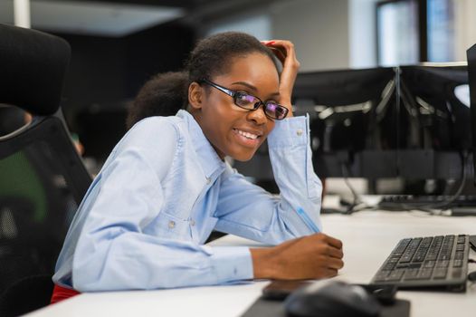 African young woman typing on a computer at her desk in the office