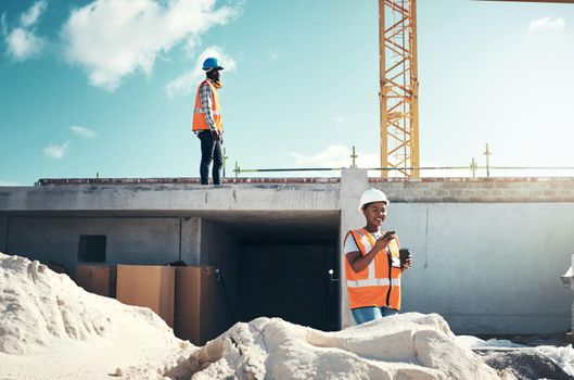 Back to constructing but first coffee. a young woman using a smartphone on a coffee break at a construction site