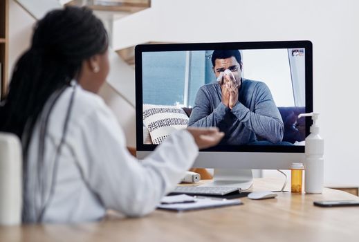 Checking in for a video visit with the doc. a young man blowing his nose during a video call with a doctor on a computer