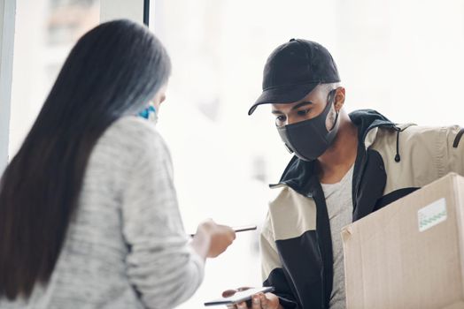 Contactless pay is for everybodys protection. a masked young man and woman using smartphones during a home delivery