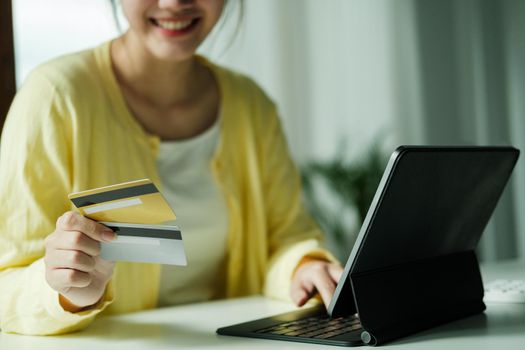 Close up asian woman using credit card for purchasing and shopping online on laptop computer.