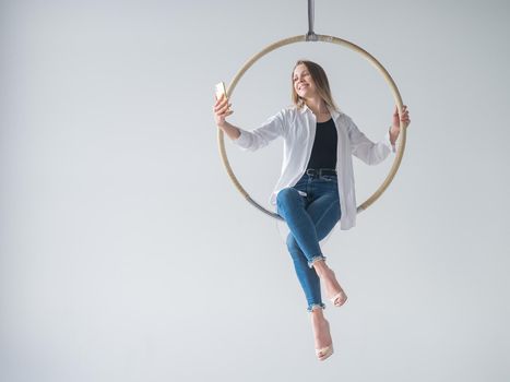 Caucasian woman gymnast on an aerial hoop takes a selfie on a smartphone