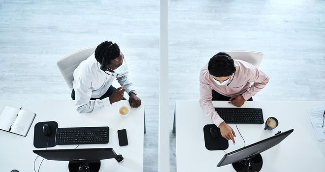 Assisting each other from a safe distance. High angle shot of two call centre agents working together in an office