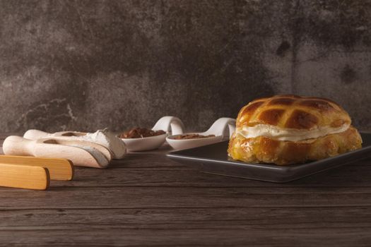 cream-filled bun covered with sugar syrup on a grey plate on a wooden table