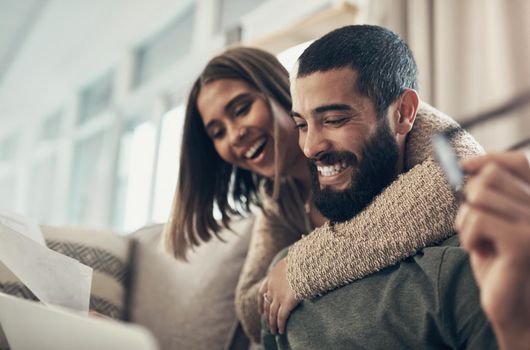 The benefits of budgeting cannot be overstated. a young couple using a laptop while going through paperwork at home