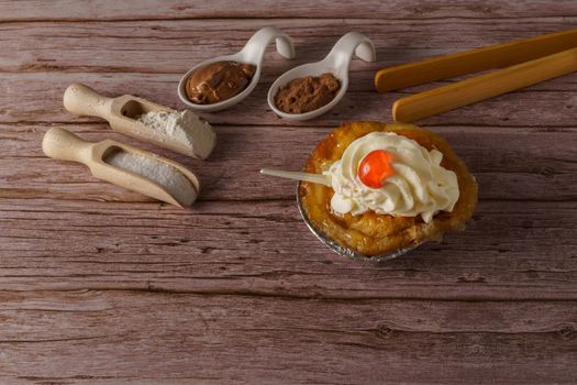 puff pastry dough cake with liqueur and cream, a cherry on top and spoon on a wooden table