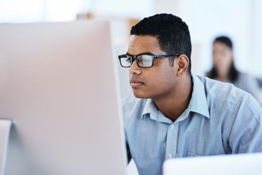 Nobody manages an IT network like he does. a young businessman using a computer in a modern office