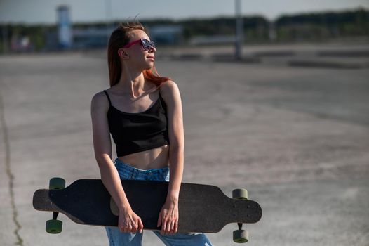 Young caucasian woman holding a long board outdoors