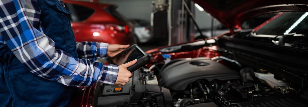 Caucasian female auto mechanic uses a special computer to diagnose faults