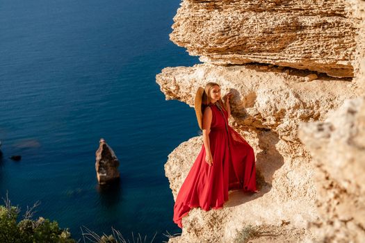 A woman in a red flying dress fluttering in the wind, against the backdrop of the sea