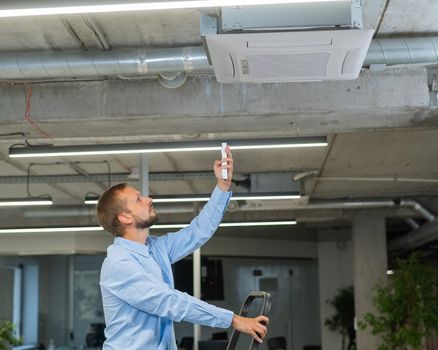 Caucasian bearded man repairing the air conditioner in the office