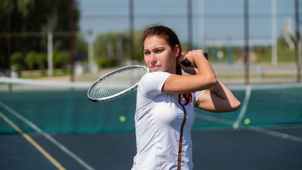 Young caucasian woman playing tennis on an outdoor court on a hot summer day