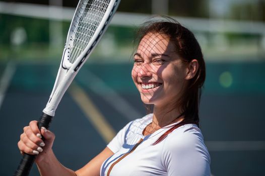 Beautiful smiling woman with a shadow from a tennis racket on her face on a sunny day.