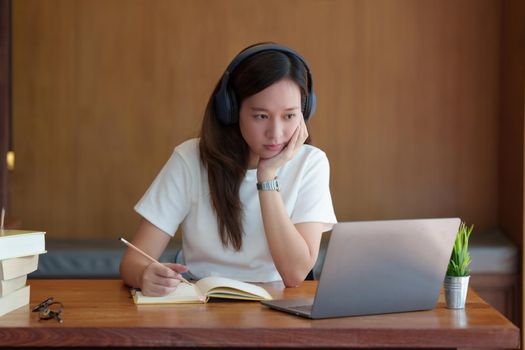 Back to school concept. Young college woman using laptop at library.