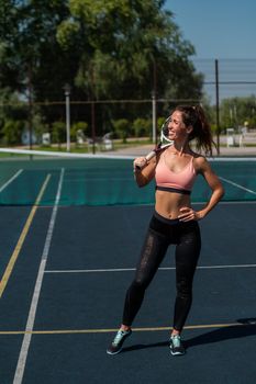 Beautiful European woman posing on a tennis court and holding a rocket.