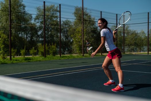 Young caucasian woman playing tennis on an outdoor court on a hot summer day