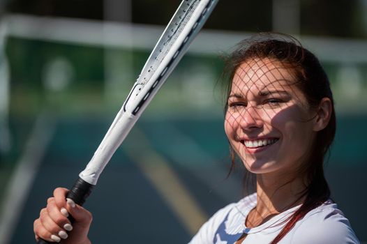 Beautiful smiling woman with a shadow from a tennis racket on her face on a sunny day.