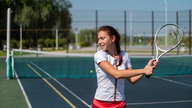 Young caucasian woman playing tennis on an outdoor court on a hot summer day