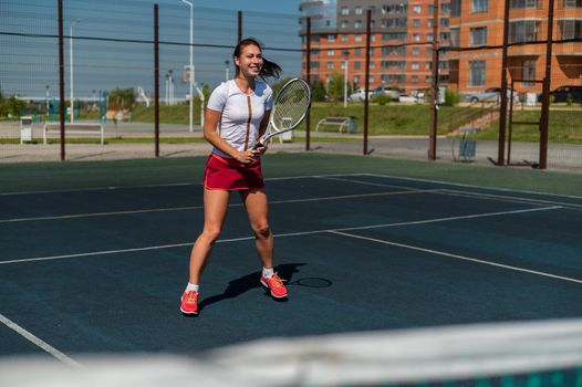 Young caucasian woman playing tennis on an outdoor court on a hot summer day