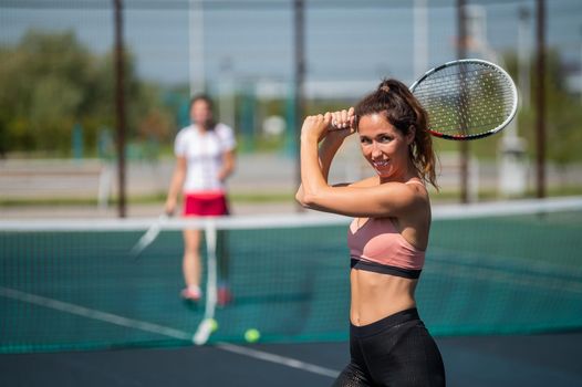 Sportive caucasian woman posing with a racket on a tennis court outdoors