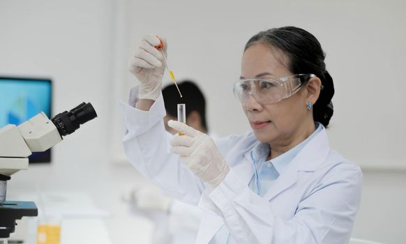 Health care researchers working in life science laboratory. Young female research scientist and senior male supervisor preparing and analyzing microscope slides in research lab..