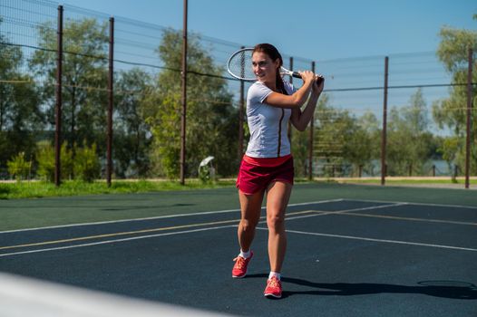 Young caucasian woman playing tennis on an outdoor court on a hot summer day