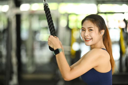 Fitness woman in sportswear exercising in gym and smiling to camera.