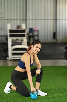 Beautiful young woman in sportswear exercising with a kettle bell.