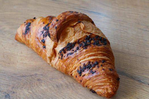 Delicious fresh baked goods. Croissant for coffee or tea. Quick breakfast or snack. A croissant lies on a wooden background