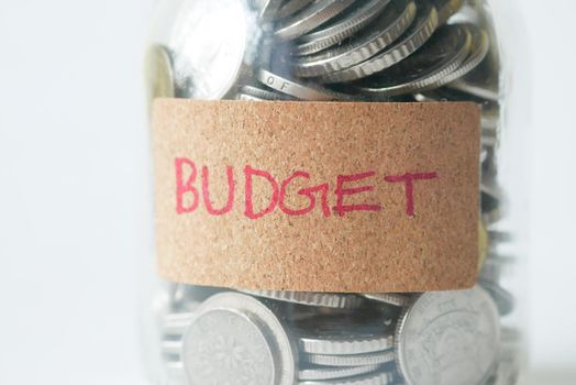 budget text on a saving coins jar on white ,