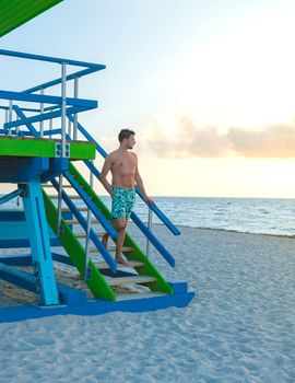 Miami beach, young men on the beach, lifeguard hut Miami beach Florida. caucasian men on the beach during sunset. European men shirtless with swim short