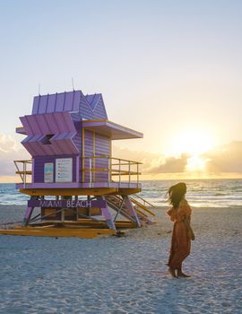 Miami Beach, a couple on the beach at Miami Florida, lifeguard hut Miami Asian women and caucasian men on the beach during sunset. Woman watching sunset on the beach