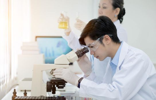 biochemical research scientist team working with microscope for coronavirus vaccine development in pharmaceutical research labolatory, selective focus.