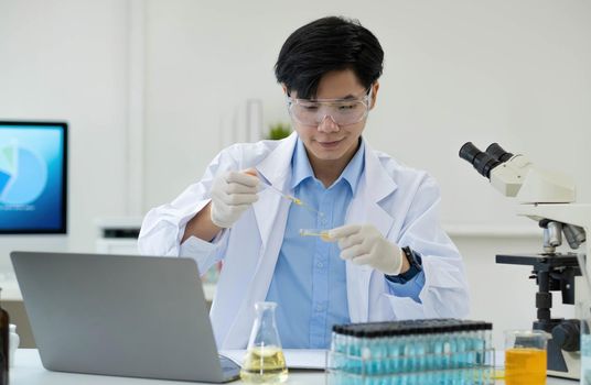 Medical Research Laboratory Portrait of a Handsome Male Scientist Using Digital Tablet Computer, Analysing Liquid Biochemicals in a Laboratory Flask.