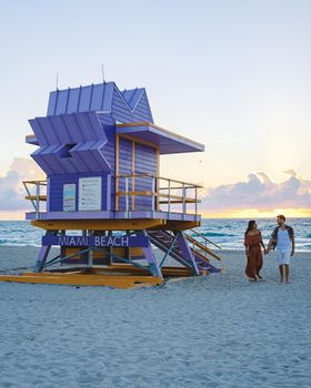 Miami Beach, a couple on the beach at Miami Florida, lifeguard hut Miami Asian women and caucasian men on the beach during sunset