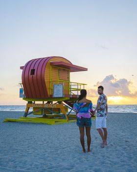 Miami Beach, a couple on the beach at Miami Florida, lifeguard hut Miami Asian women and caucasian men on the beach during sunset