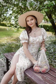 An attractive long-haired woman walks in the spring in the park of blooming apple trees. Spring portrait of a woman