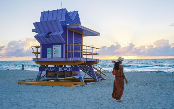 Miami Beach, a couple on the beach at Miami Florida, lifeguard hut Miami Asian women and caucasian men on the beach during sunset. Woman watching sunset on the beach