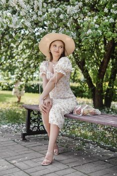 An attractive long-haired woman walks in the spring in the park of blooming apple trees. Spring portrait of a woman