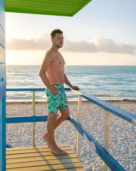 Miami beach, young men on the beach, lifeguard hut Miami beach Florida. caucasian men on the beach during sunset. European men shirtless with swim short