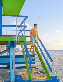 Miami beach, young men on the beach, lifeguard hut Miami beach Florida. caucasian men on the beach during sunset. European men shirtless with swim short